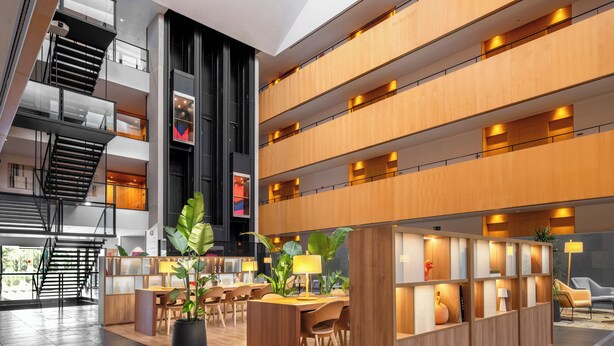 A modern hotel lobby with a central seating area, a staircase, and a reception desk. - INNSiDE by Meliá Barcelona Aeropuerto (El Prat de Llobregat)