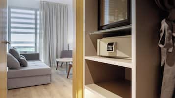 Una habitación de hotel moderna con sofá, una mesita, televisor y una bata colgada en la pared.