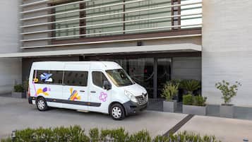Una camioneta blanca estacionada frente a un edificio moderno con grandes ventanales y techo plano.