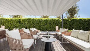 An outdoor patio with wicker furniture, a round table, and a white canopy. - INNSiDE by Meliá Barcelona Aeropuerto (El Prat de Llobregat)