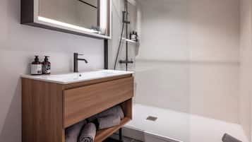 Ein modernes Badezimmer mit Waschtisch aus Holz, einem großen Spiegel und einer Duschkabine.