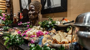 A buffet table with various food items, including bread, cheese, and a plate with a knife and fork.
