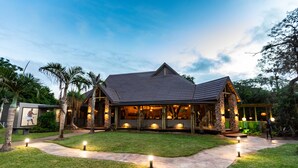 A house with a sloped roof, stone pillars, and a well-lit entrance.