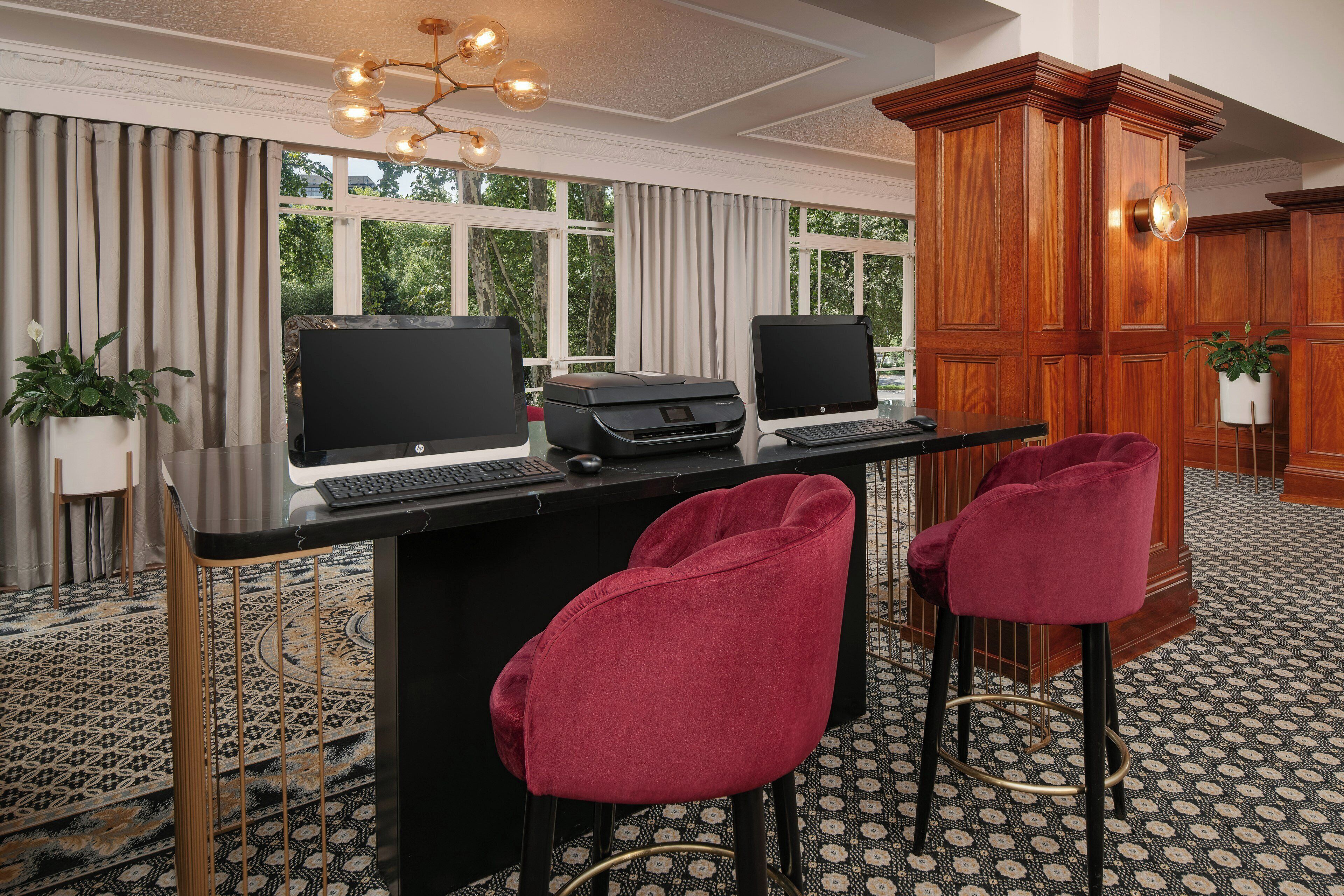 A room with a desk, two monitors, a printer, and two red chairs.