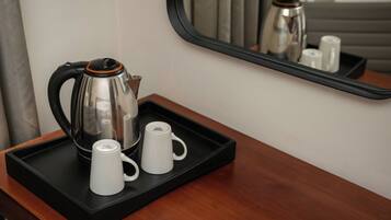 Una zona de cafè amb una tetera, dues tasses blanques i una safata sobre una superfície de fusta.
