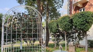 A garden with a metal gazebo, a birdbath, and neatly trimmed bushes.