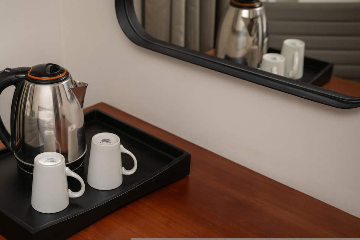 A coffee maker, two white mugs, and a tray on a wooden table.