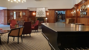 A spacious lobby with a grand piano, comfortable seating, and a decorative ceiling.