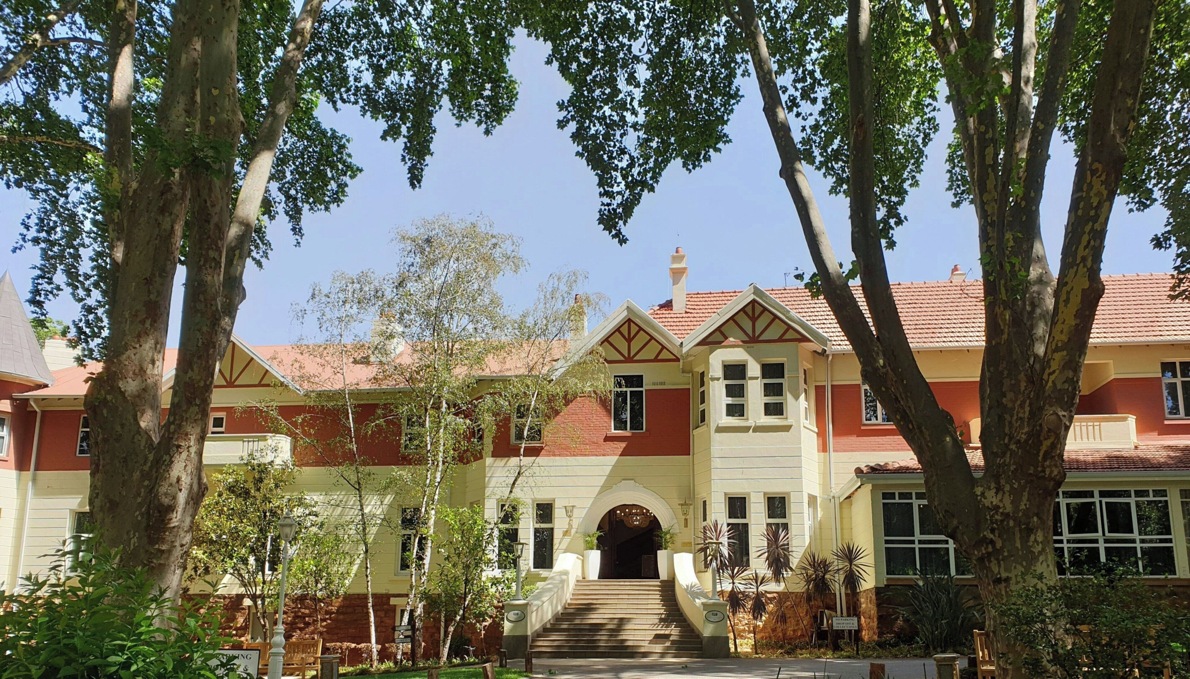 A two-story building with a red-tiled roof, a central entrance with steps, and a symmetrical facade.