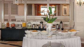 Montaje de bufé con diversas opciones de comida y bebidas, un centro de mesa con planta decorativa y una decoración de estilo tradicional.