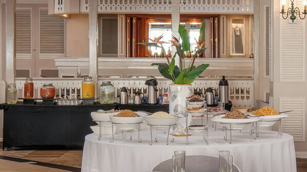 Montaje de bufé con diversas opciones de comida y bebidas, un centro de mesa con planta decorativa y una decoración de estilo tradicional.