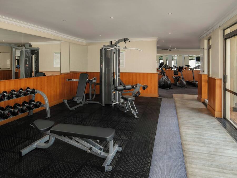 Une salle de sport équipée de matériel d’exercice, d’un banc et d’haltères.