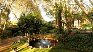 Un jardín con un estanque, estatuas y un edificio al fondo.