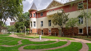 A multi-story building with a central courtyard featuring a circular brick pathway and a fountain.