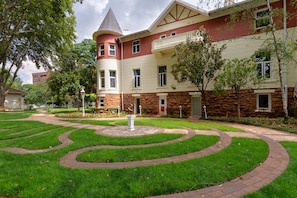 A multi-story building with a central courtyard featuring a circular brick pathway and a fountain. - Holiday Inn Johannesburg Sunnyside Park by IHG (Johannesburg)