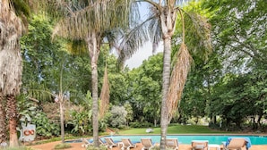 A pool area with lounge chairs and palm trees.