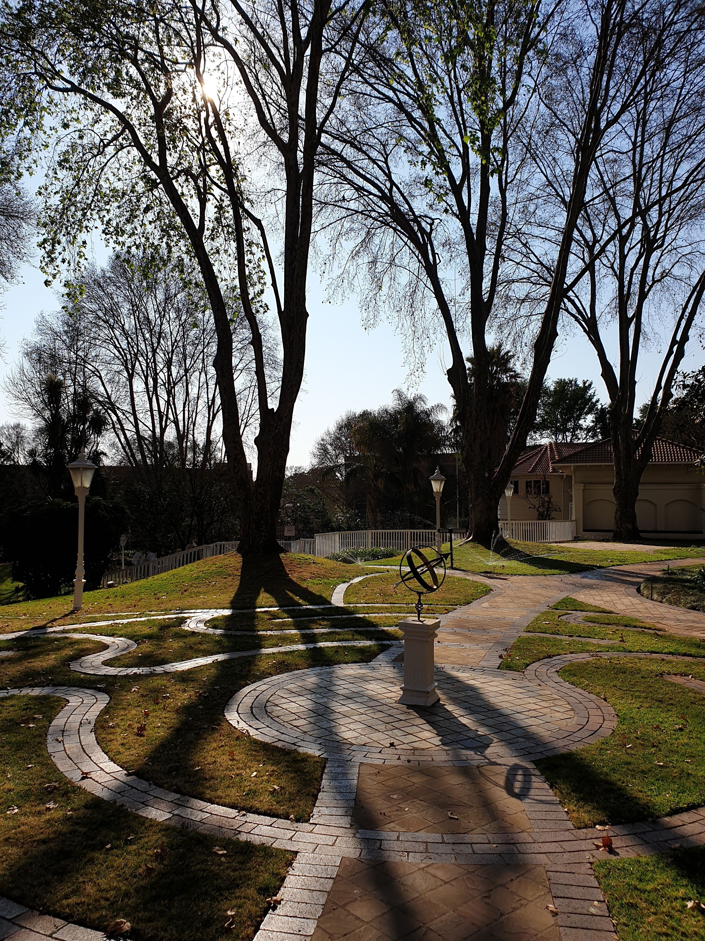 A park with a winding pathway, trees, and a globe sculpture.