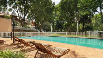 Piscina com espreguiçadeiras e cerca branca.