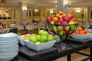 Un área de buffet con diversas frutas y fuentes de comida.