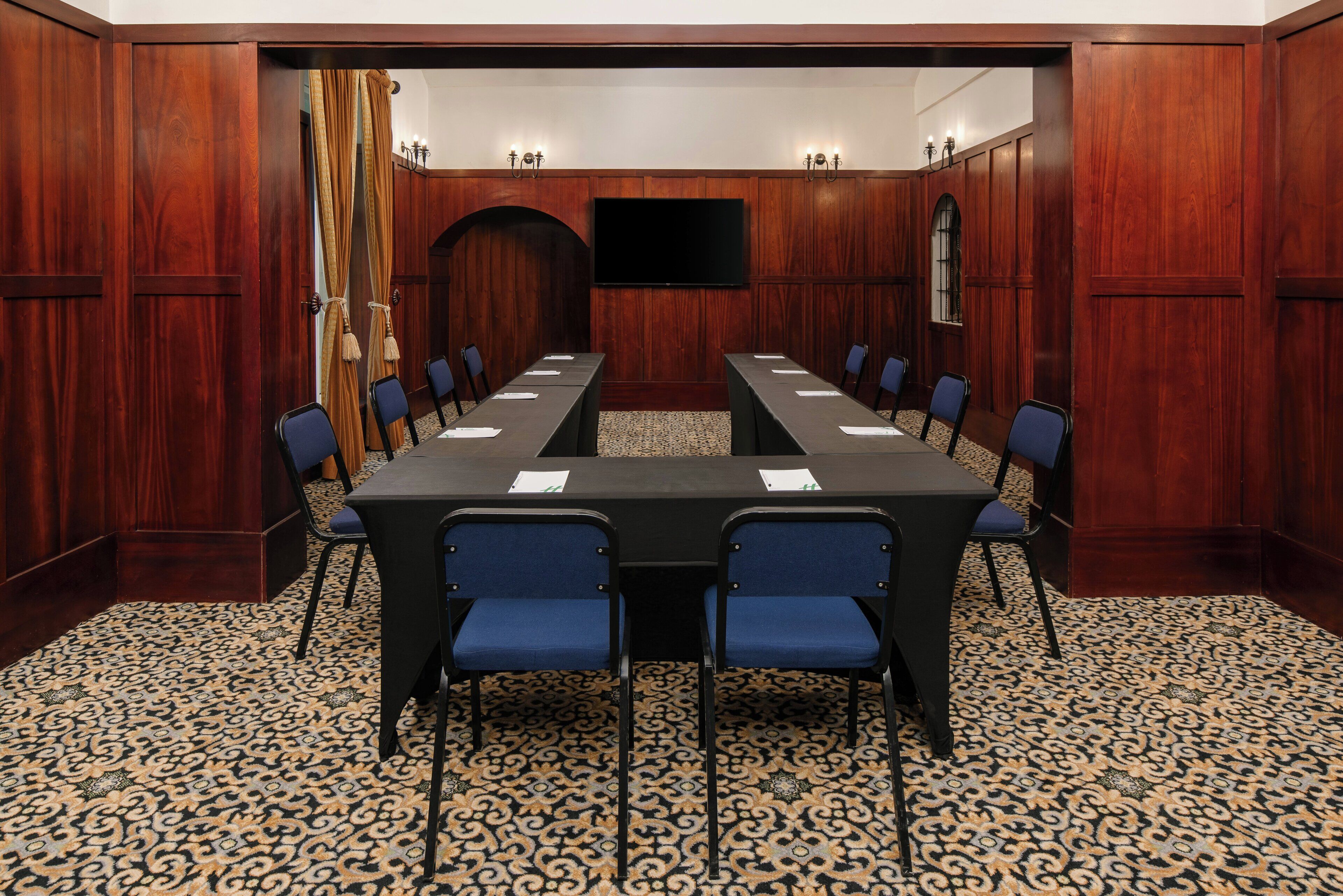 Une salle de conférence avec une longue table, des chaises et un tapis à motifs.