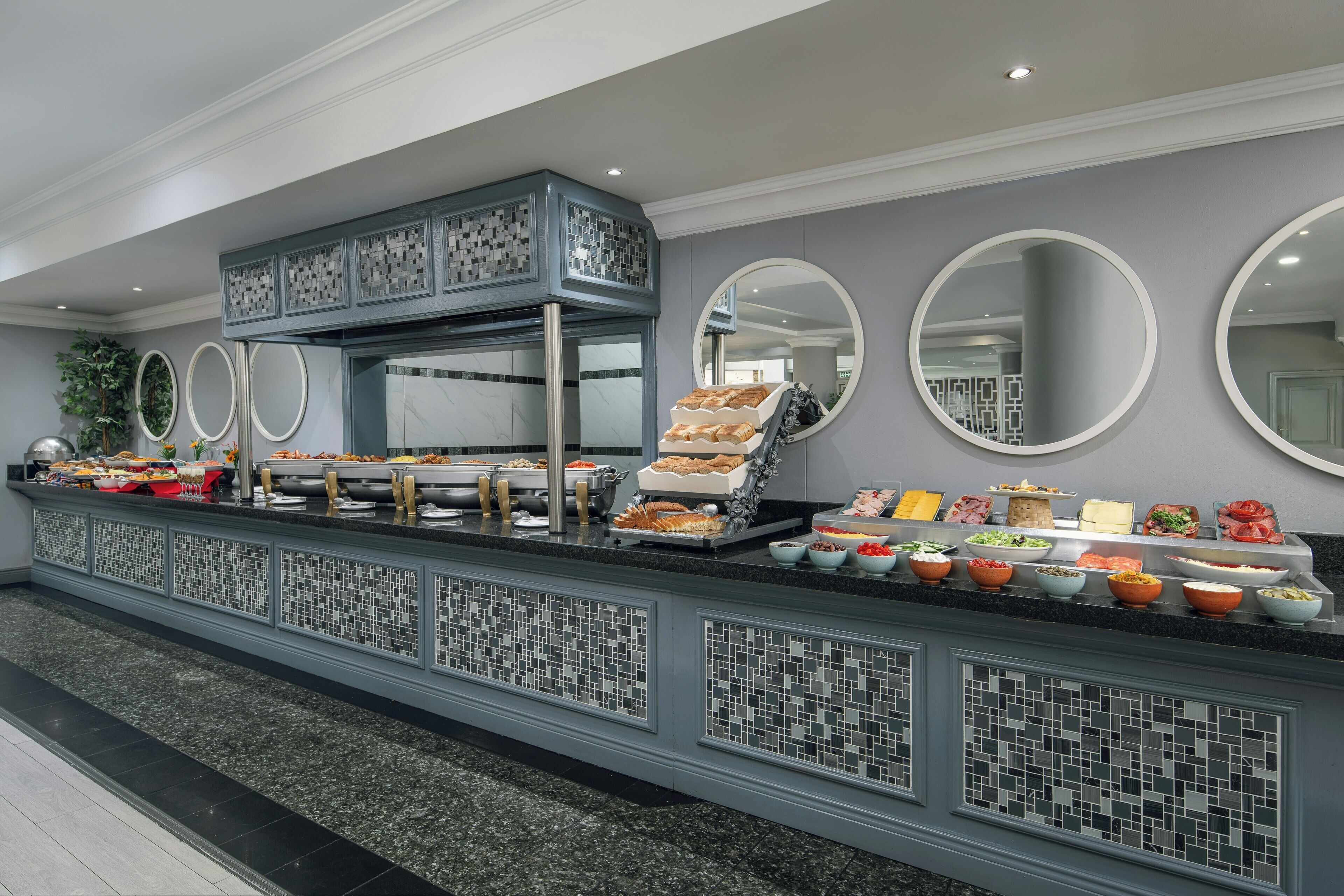 A buffet setup with various food items and a decorative mirror.