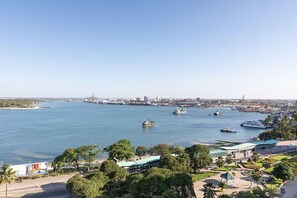 A coastal cityscape with a marina, boats, and a clear sky.