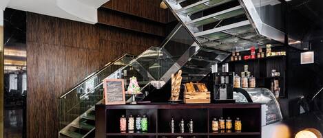 Ein modernes Interieur mit einer Treppe, einer Auswahl an Backwaren und Regalen mit verschiedenen Lebensmitteln.