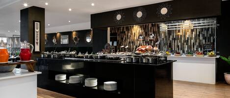 A modern breakfast bar with a variety of food options, including fruits and pastries, and a coffee station.