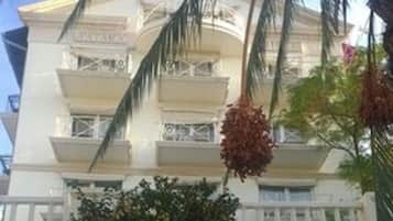 Un hotel de varios pisos con fachada blanca, base de piedra y una escalera central.