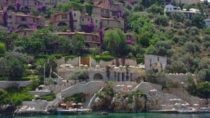 A coastal town with terraced buildings, a stone bridge, and a clear blue sea. - Patara Prince Hotel & Resort (Kas)