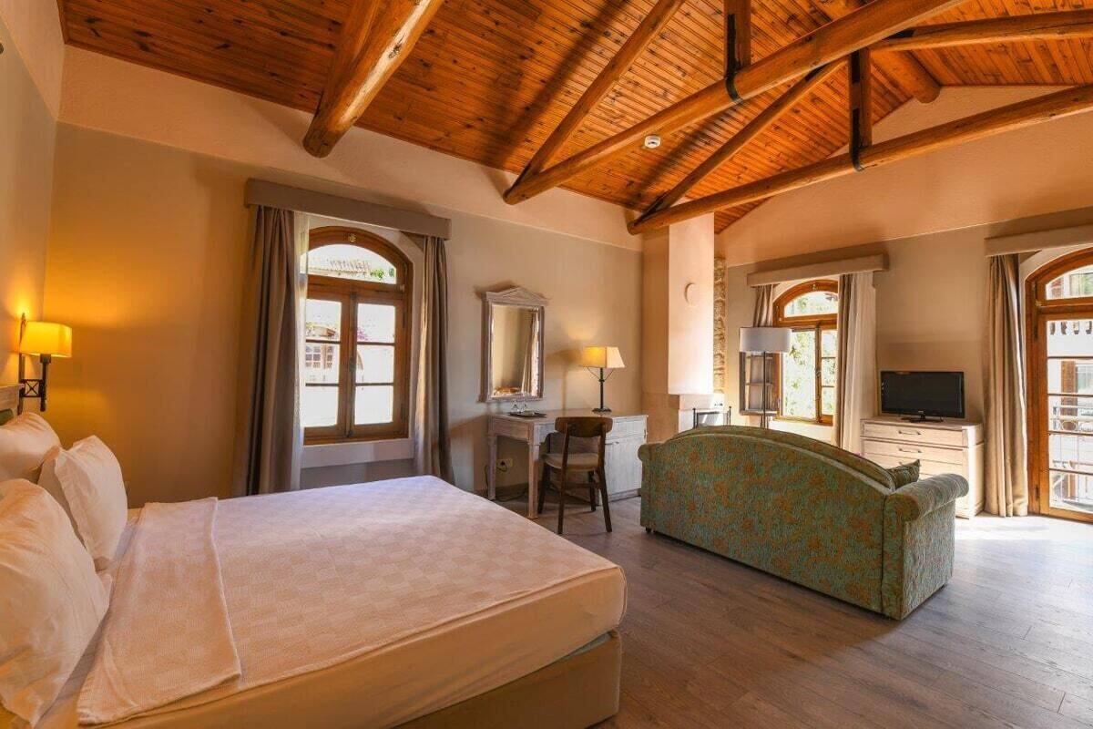A hotel room with a bed, a desk, a chair, a television, and a sofa.