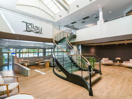 Eine geräumige Lobby mit einer geschwungenen Glasstaircase, Sitzbereichen und einem Schild für die Küche des Sonoma County.. Sheraton Sonoma Wine Country Petaluma