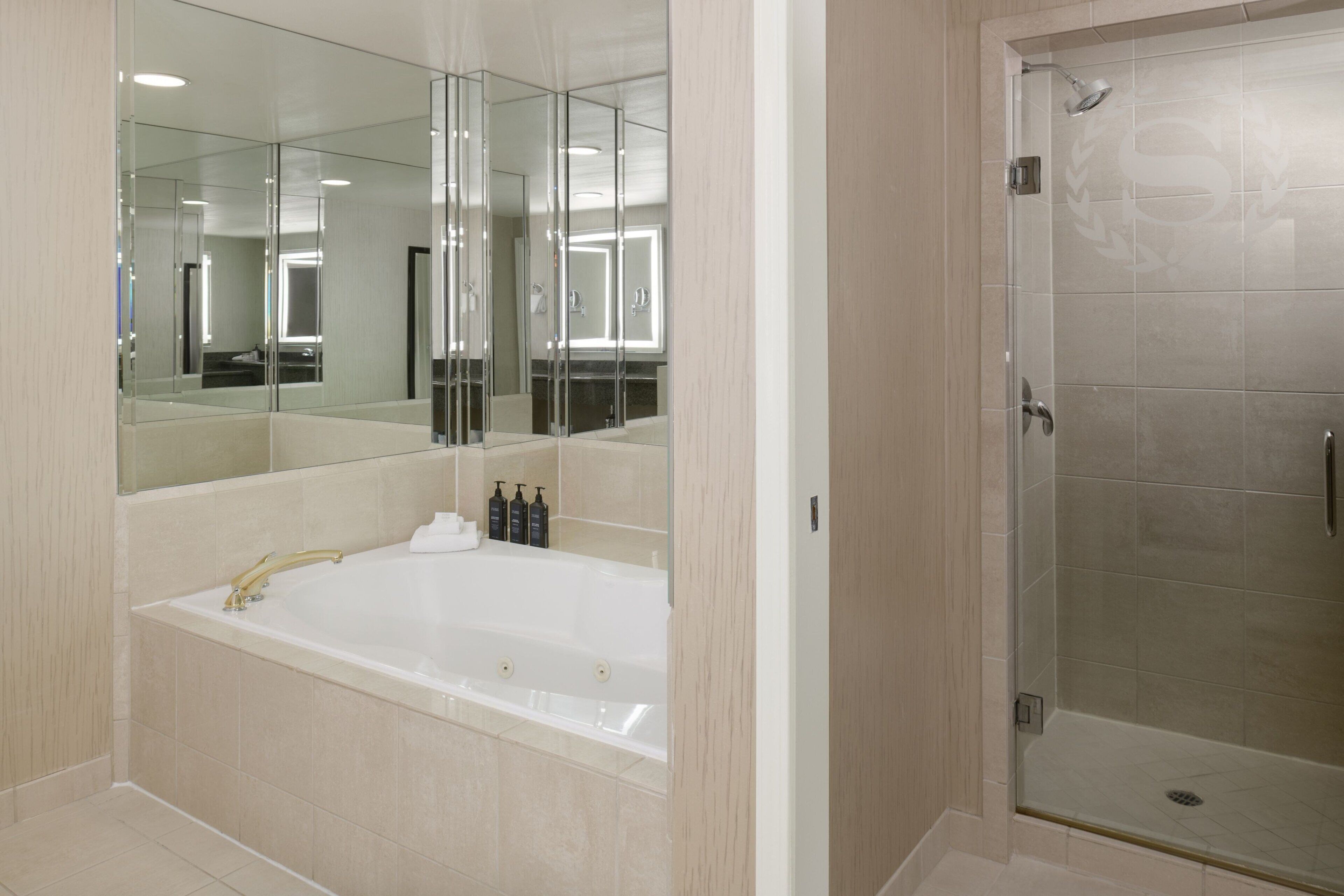 Un baño moderno con una bañera grande, cabina de ducha de vidrio y un espejo que refleja la habitación.
