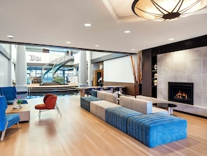 Un hall dâhĂŽtel moderne dotĂ© dâune cheminĂ©e, dâun espace salon et offrant une vue sur lâatrium.