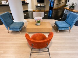 Un hall con dos sillones azules, una mesa de centro de madera y una butaca naranja.