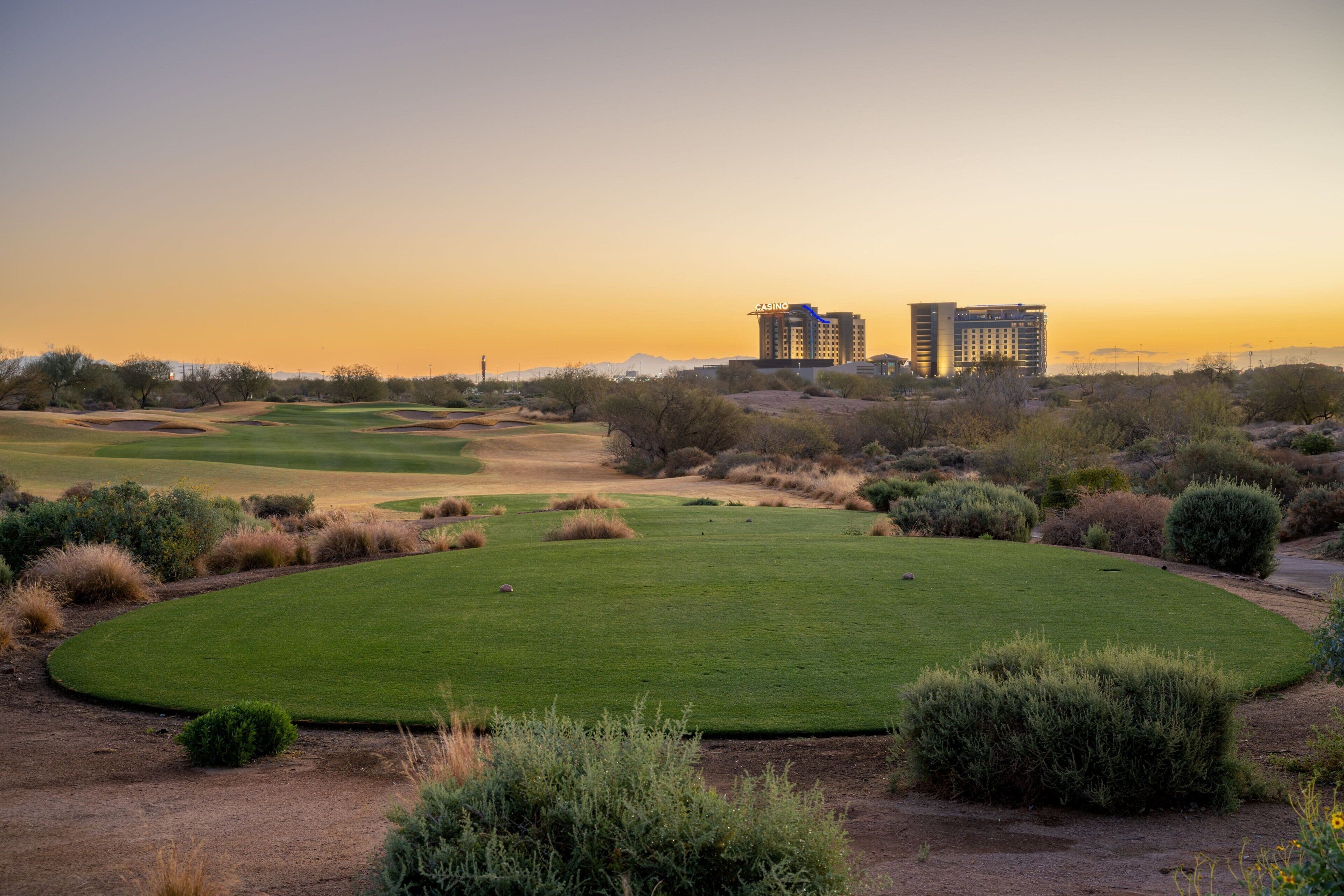 A golf course with two buildings in the background.
