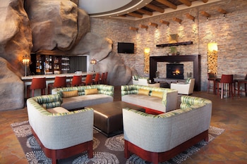 A rustic interior with exposed wooden beams, a stone fireplace, leather seating, and a bar area. at Sheraton Grand at Wild Horse Pass