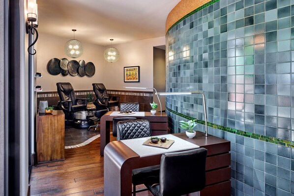 A modern dining area with a curved wall, a wooden reception desk, and several black leather chairs. - Sheraton Grand at Wild Horse Pass (Chandler)