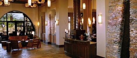 A lobby with a mosaic floor, a reception desk, and a stone wall.