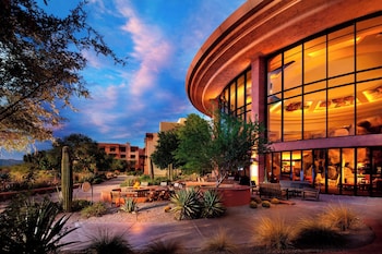 A resort pool area with multiple lounge chairs and umbrellas, surrounded by a wooden pergola structure. at Sheraton Grand at Wild Horse Pass