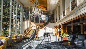 A grand lobby with a staircase, large windows, and elegant furniture. - Der Sonnenhof (Bad Woerishofen)