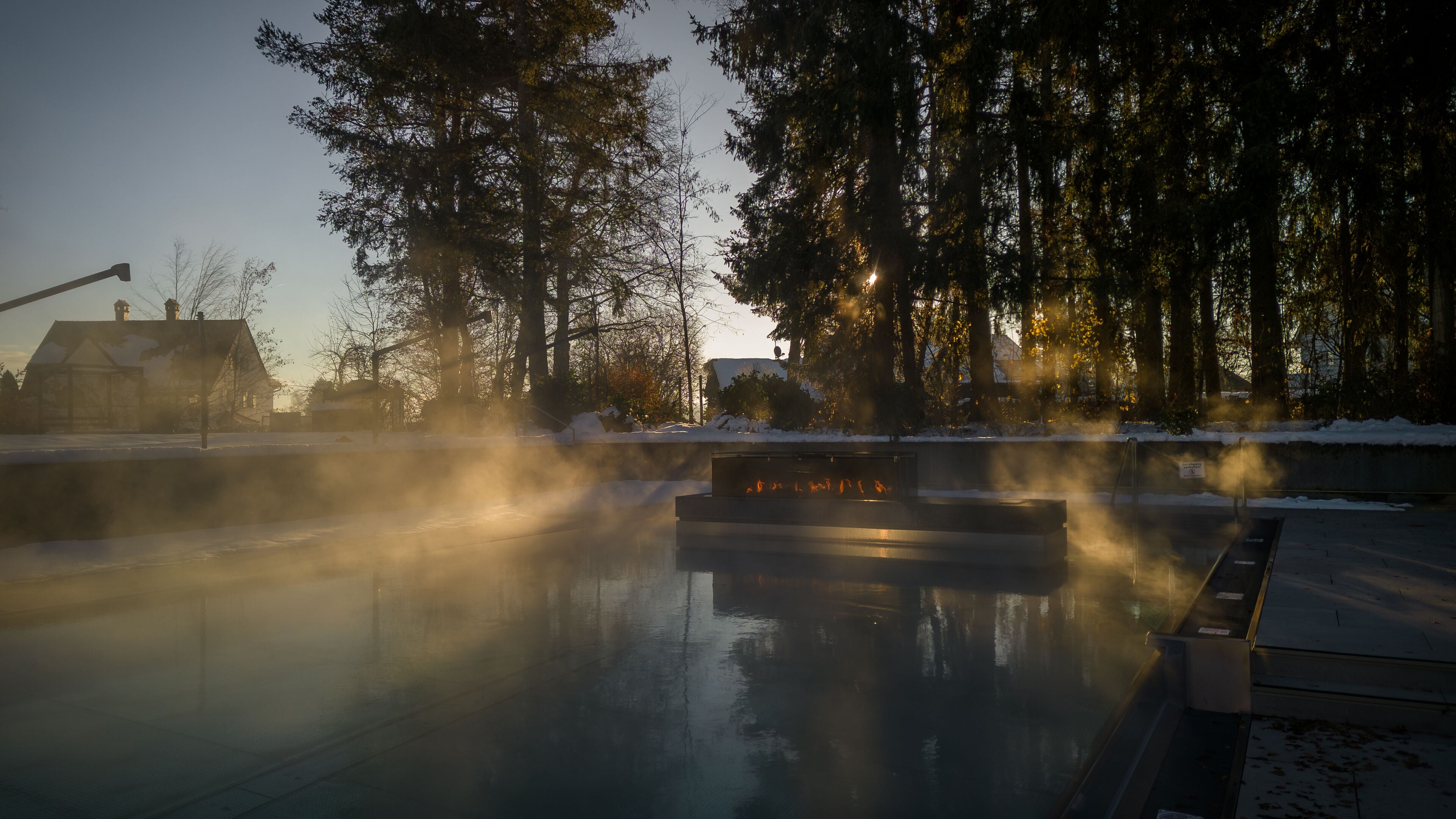 A steam room with a sauna, surrounded by snow-covered ground and trees.