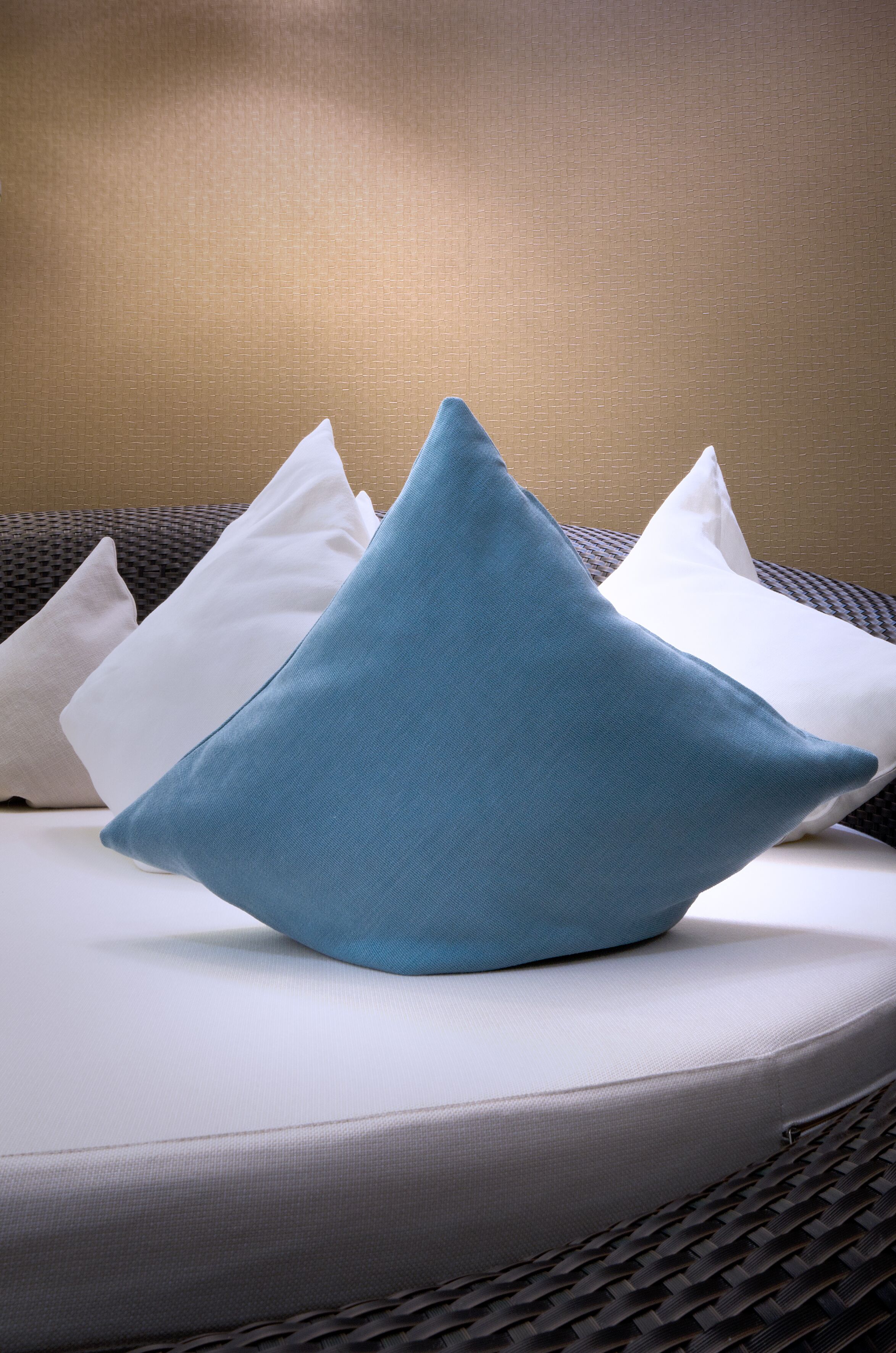 A bed with a white mattress and a blue pillow.