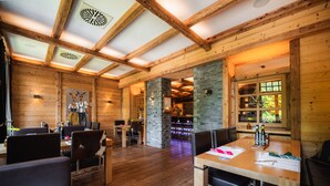 A wooden interior with a dining area, stone pillars, and a bar. - Der Sonnenhof (Bad Woerishofen)