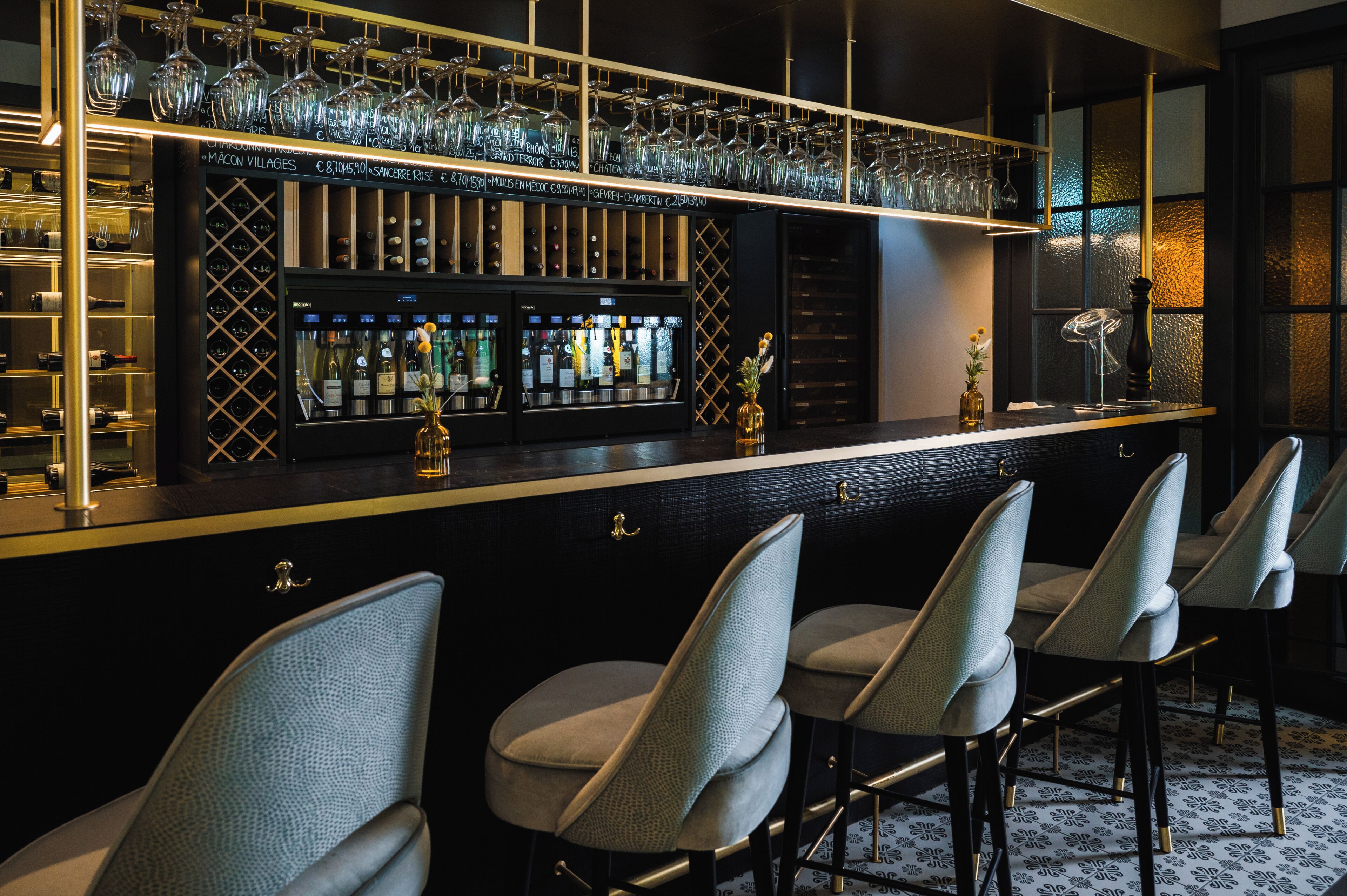 Una zona de bar con una estantería para vinos, taburetes y un jarrón decorativo.