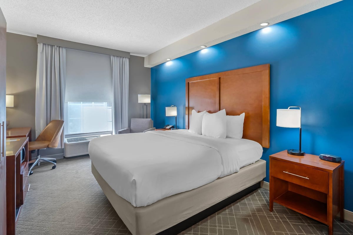 A hotel room with a large bed, a desk, and a chair.