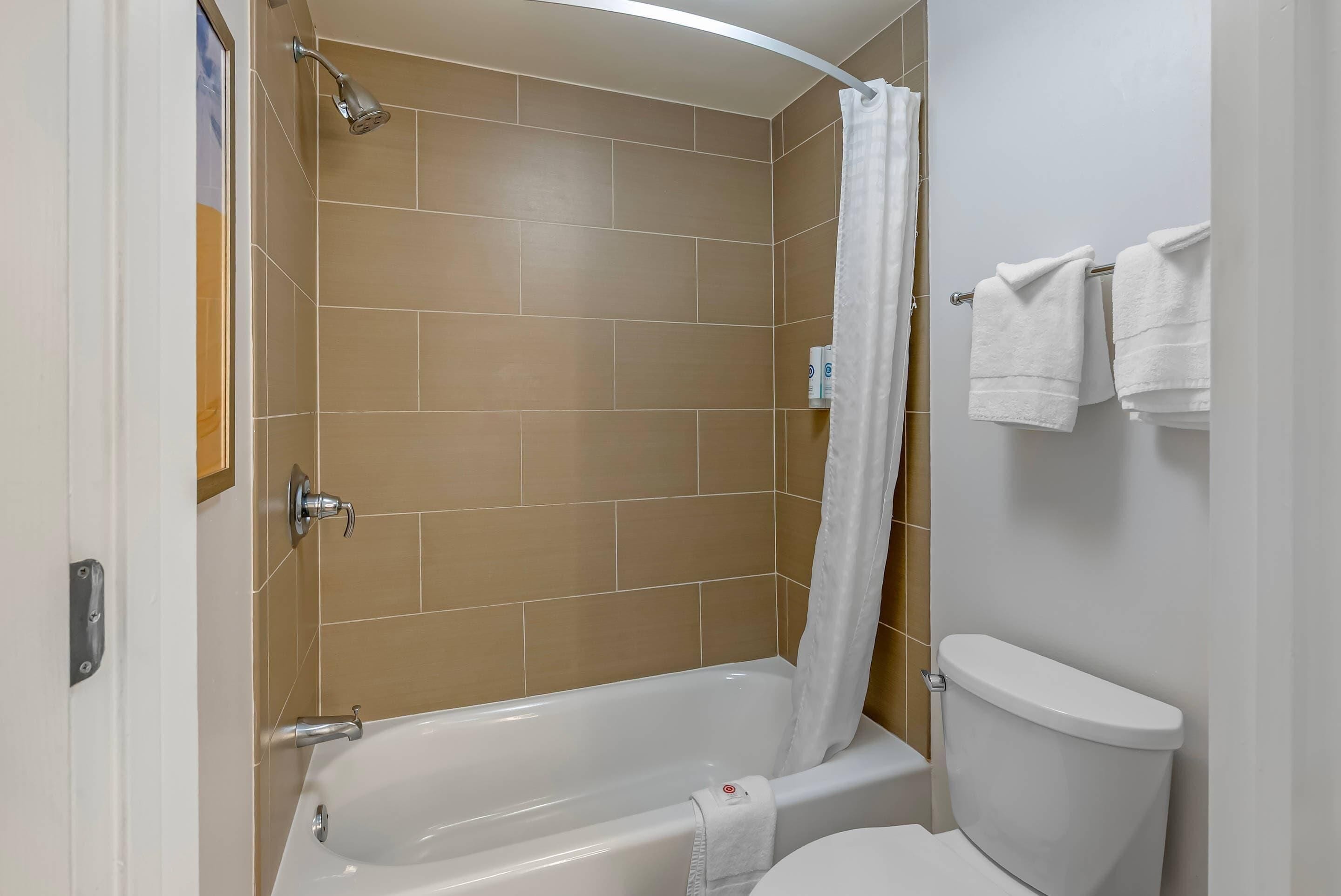 A bathroom with a bathtub, shower, and toilet.
