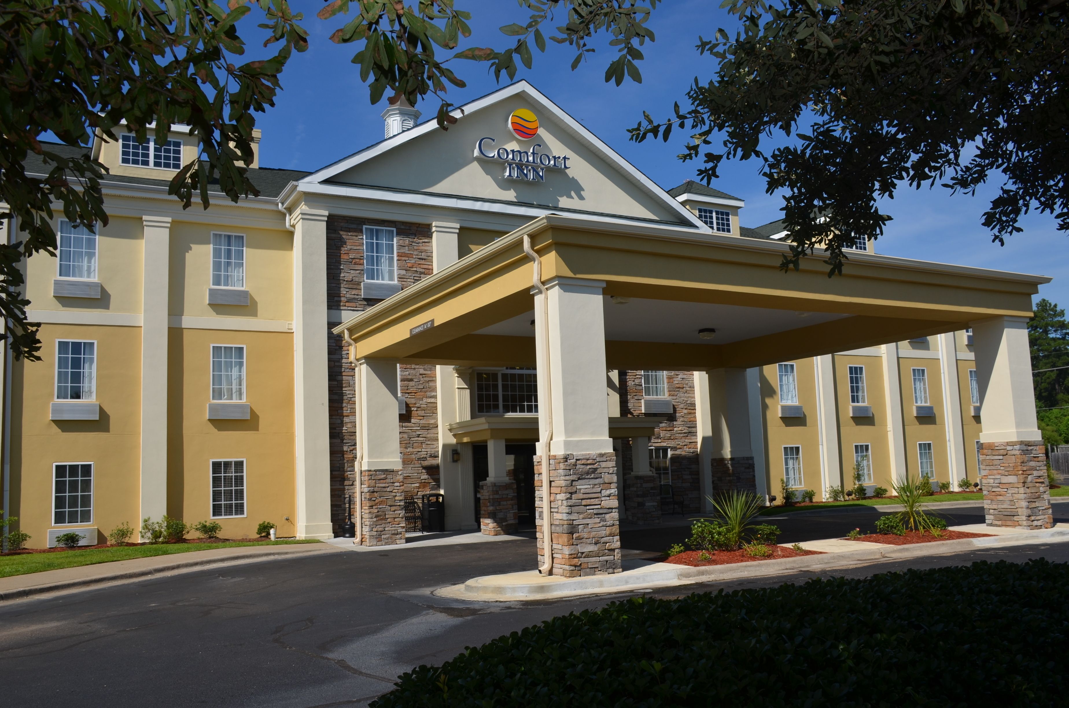 A Comfort Inn hotel with a covered entrance, stone pillars, and a clear blue sky.
