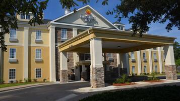 A Comfort Inn hotel with a covered entrance, stone pillars, and a clear blue sky.