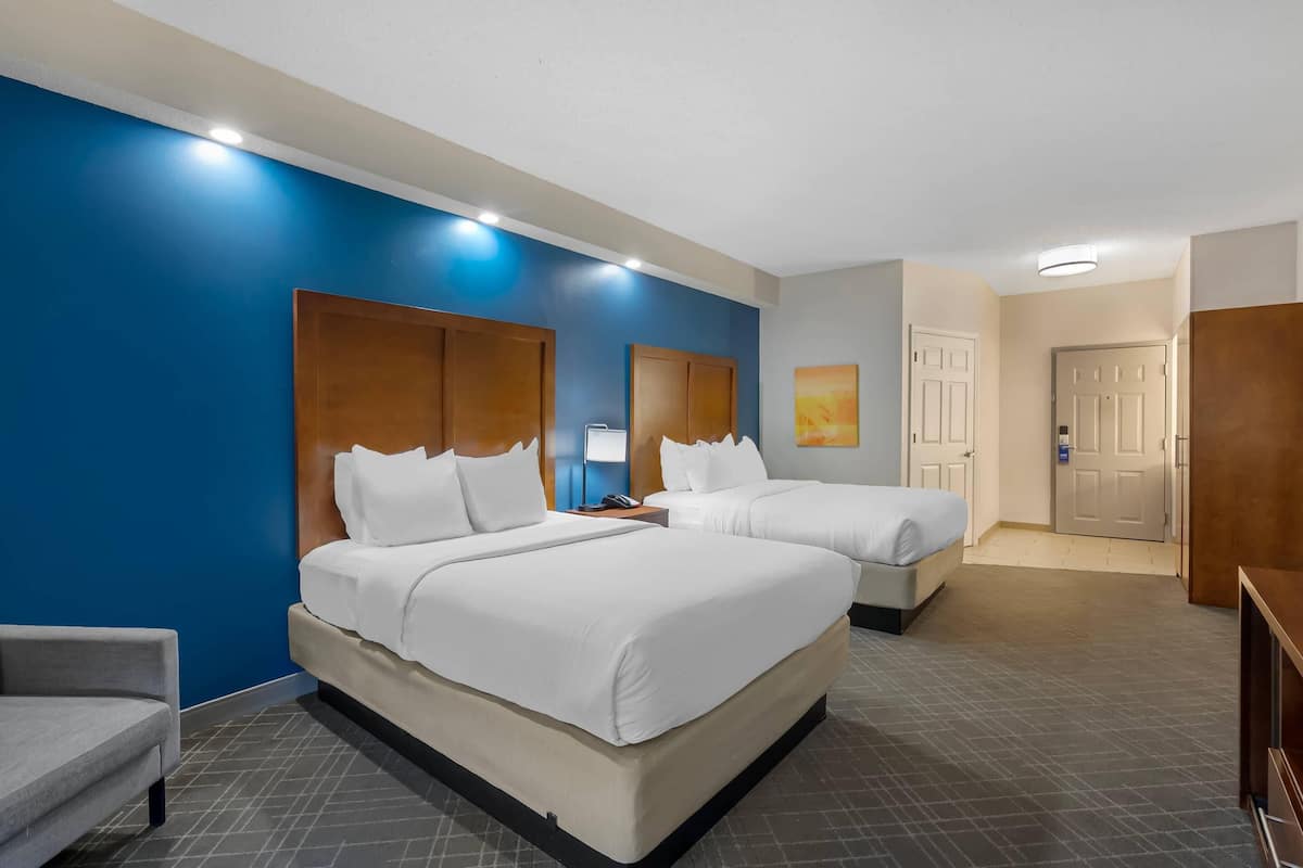 A hotel room with two beds, a desk, and a chair.